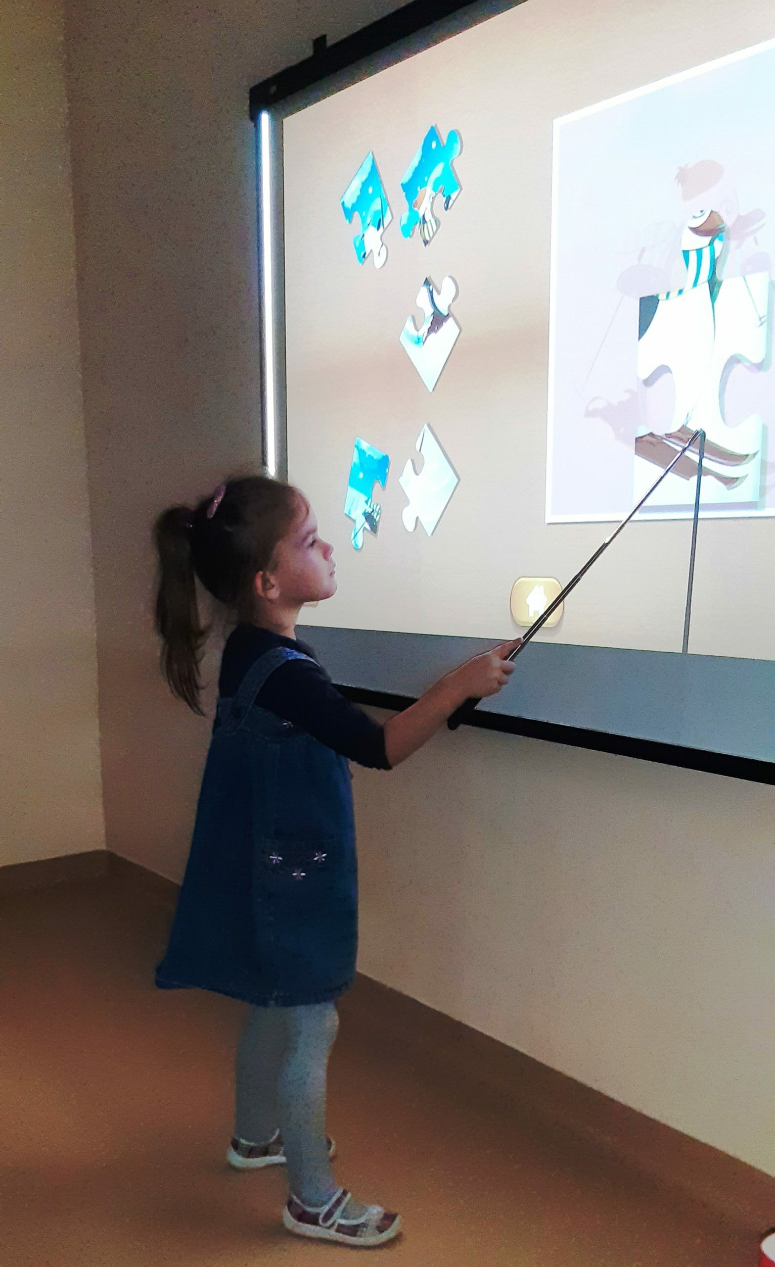 dziecko układa puzzle na tablicy multimedialnej